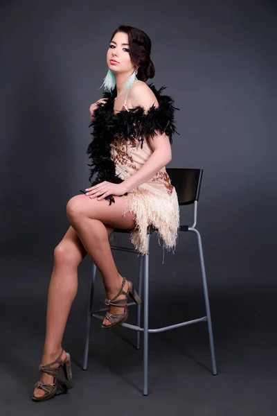 用鸵鸟羽毛做的布吕内特美女坐在椅子上 20年了口头照片 — 图库照片