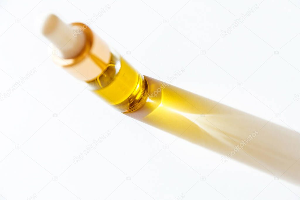 cosmetic oil in glass bottle with white pipette on white background with copy space. Horizontal photo. Top view