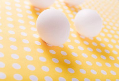 Sarı arka planda benekli beyaz tavuk yumurtaları.