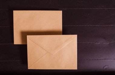 Siyah ahşap arka planda iki kahverengi zarf.