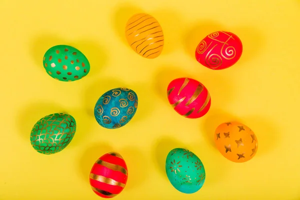 Colored easter eggs on a yellow background. Top view