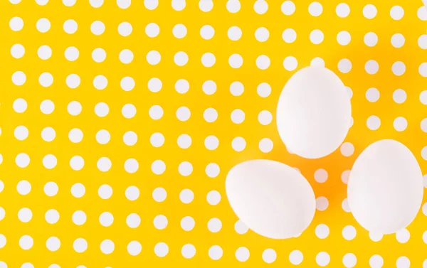 Huevos de pollo blancos sobre fondo amarillo con patrón de lunares —  Fotos de Stock