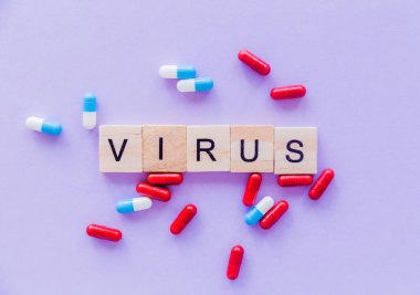 Virüs kelimesi tahta bloklardan ve mor arkaplandaki haplardan oluşuyordu. Yatay fotoğraf