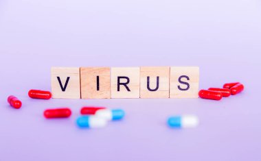 Virüs kelimesi tahta bloklardan ve mor arkaplandaki haplardan oluşuyordu. Yatay fotoğraf