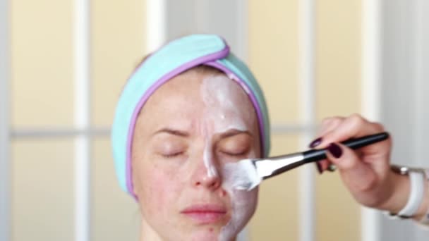 メイクアーティストは 化粧を適用する前に 女の子の顔に保湿マスクを適用します 手順は自宅で行われます ビデオ — ストック動画
