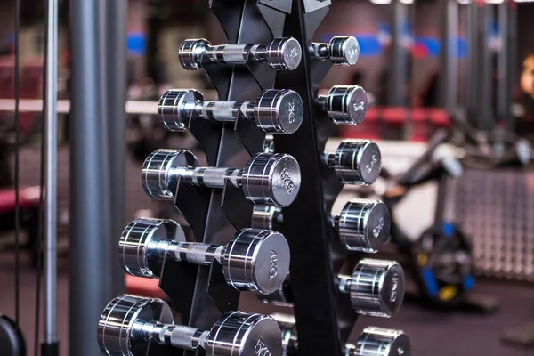 A rack with metal dumbbells in the gym. Horizontal photo