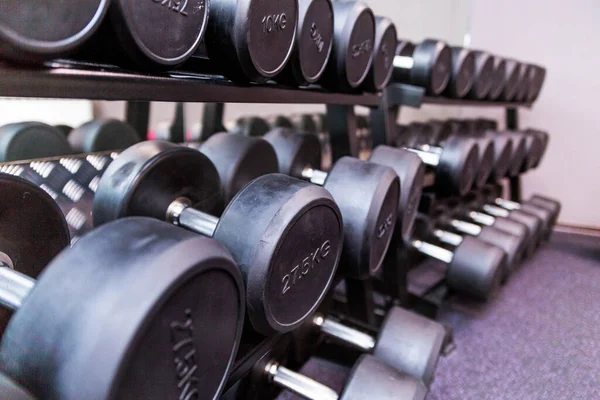 Dumbbells in a dark gym in a row. Horizontal photo