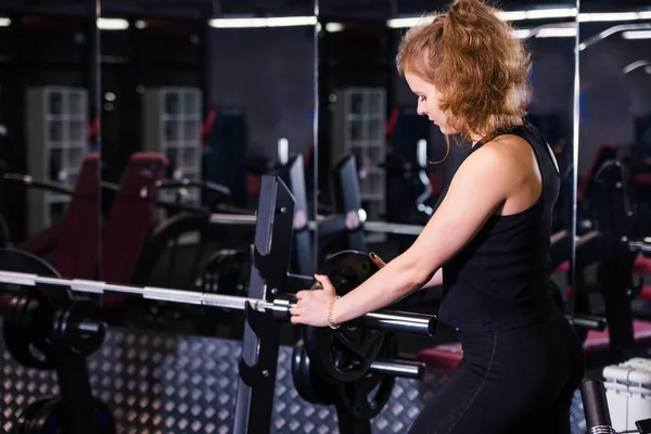 Spor salonunda halterle poz veren atletik bir kız. Yatay fotoğraf