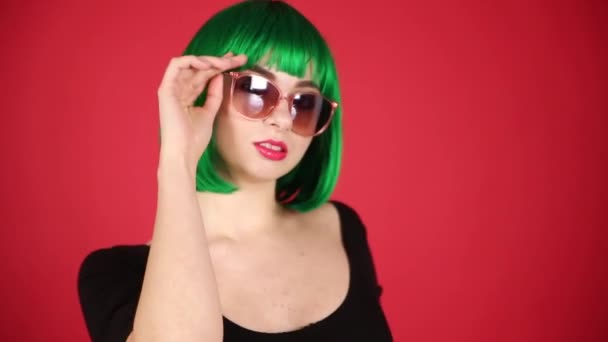 Bella Ragazza Una Parrucca Verde Bicchieri Rosa Smorfie Scherza Intorno — Video Stock