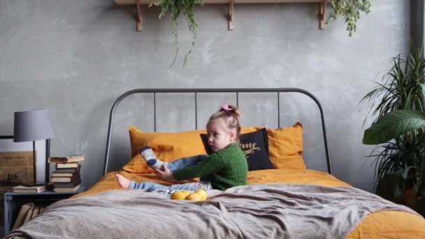 Κοριτσάκι Πράσινο Πουλόβερ Και Μπλε Τζιν Κάλτσες Στο Κρεβάτι Βίντεο — Αρχείο Βίντεο