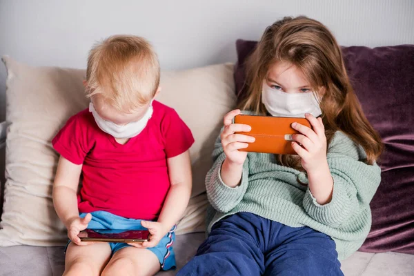 Dos Niños Están Sentados Sofá Casa Con Máscaras Médicas Blancas — Foto de Stock