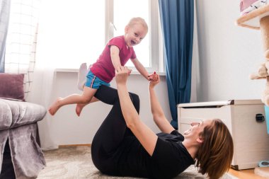 Pilates, Yoga, Evde Dizüstü bilgisayar önünde Spor yaparken Mutlu Anne ve Çocuk Uçan Uçak Oynuyor. Yatay fotoğraf