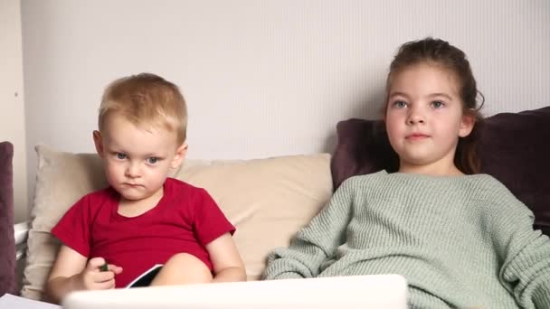 两个快乐的孩子 一个男孩和一个女孩 穿着家居服坐在沙发上 在笔记本电脑上看视频 — 图库视频影像