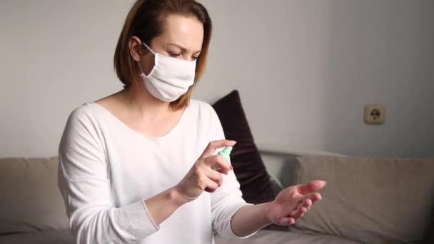 戴白色医疗面罩的妇女使用防腐剂喷雾消毒双手 — 图库视频影像