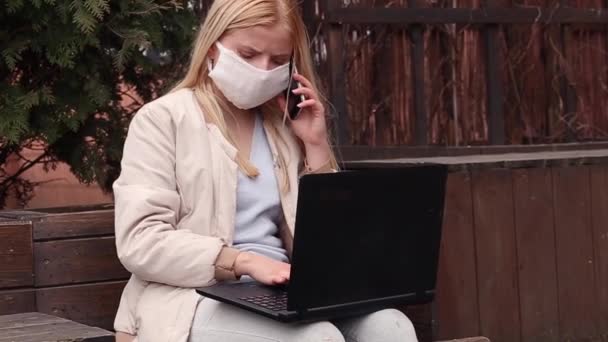 Menina Séria Com Uma Máscara Protetora Rosto Laptop Joelhos Falando — Vídeo de Stock