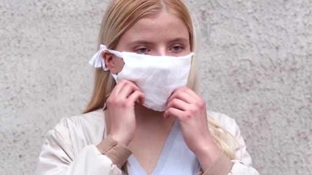 Flicka Framför Grå Vägg Sätter Sig Vit Medicinsk Mask Video — Stockvideo