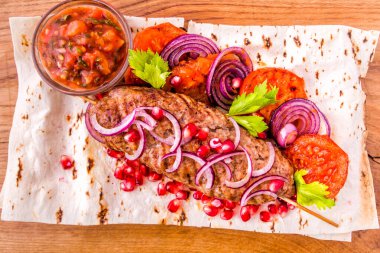 Kebap, şişte et, pide ekmeği, yanında soğan ve domates, tahtadan yapılmış nar tohumu ve sos. Yatay fotoğraf