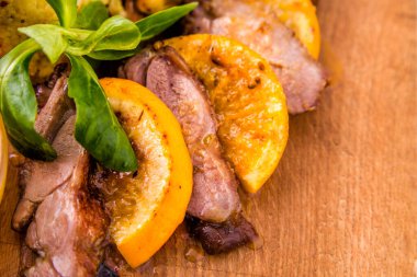 Kuru erik, kayısı ve ahşap bir tahtanın üzerinde portakal sosuyla zerdeçal eşliğinde sulu ördek göğsü. Yatay fotoğraf