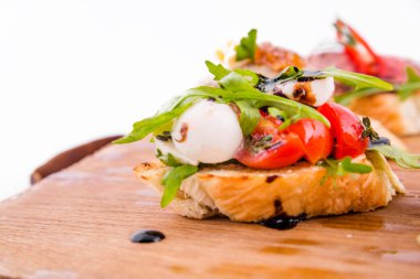 Beyaz arka planda tahta bir tahtanın üzerinde çeşitli bruschett 'ler vardı. Yatay fotoğraf