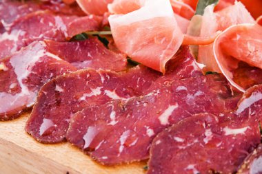 Beyaz arka planda ahşap bir tahtanın üzerinde çeşitli etler.