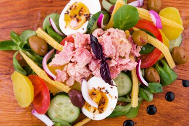 Ton balıklı salata, taze sebzeler - salatalık ve domates, konserve mısır, haşlanmış patates, şifalı otlar, soğanlar, ahşap tepside zeytin, yemek,.