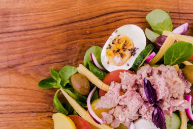 Ton balıklı salata, taze sebzeler - salatalık ve domates, konserve mısır, haşlanmış patates, şifalı otlar, soğanlar, ahşap tepside zeytin, yemek,.