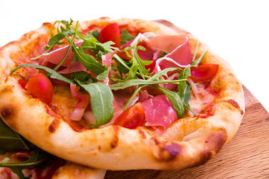 Jambonlu pizza, domates, ahşap tabakta roka. Kapatın. Yatay fotoğraf