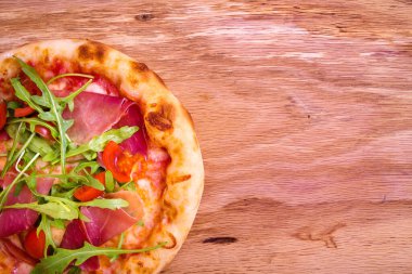 Jambonlu pizza, domates, ahşap arka planda roka. Yatay fotoğraf