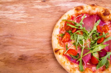 Jambonlu pizza, domates, ahşap arka planda roka. Yatay fotoğraf