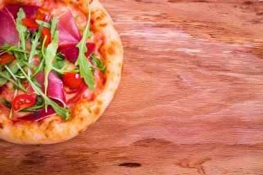 Jambonlu pizza, domates, ahşap arka planda roka. Yatay fotoğraf