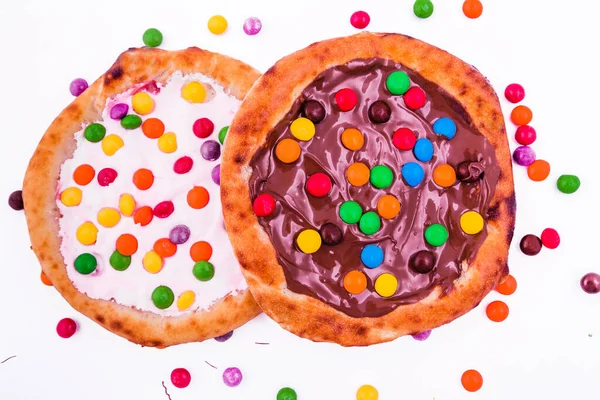 Sweet pizza with marshmallow sauce and colored sweets, chocolate pizza on a white plate. Horizontal photo