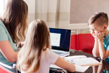 Annem dizüstü bilgisayara bakarken çocuklarıyla ödev yapıyor. Yatay fotoğraf