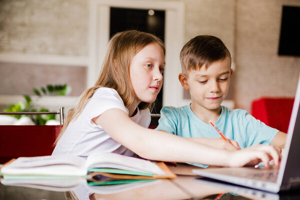 Boy and girl, brother and sister study at home. Older sister helps younger brother do homework. Horizontal photo
