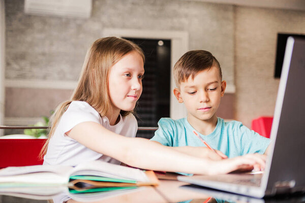Boy and girl, brother and sister study at home. Older sister helps younger brother do homework. Horizontal photo