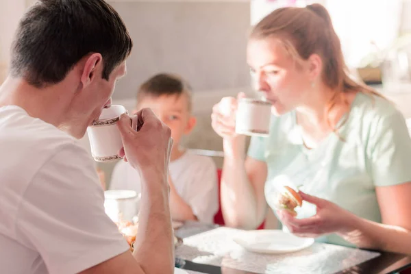 Une famille heureuse s'est rassemblée au petit déjeuner dans la cuisine, buvant du thé et parlant. Focus sur un homme avec une tasse de thé — Photo