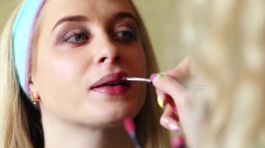 Makyöz bir kıza makyaj yapar, dudaklarını boyar. Video