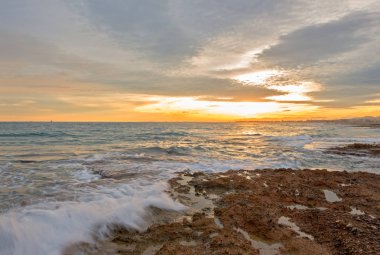 Çok Bulutlu bir gün batımı sakin denizde