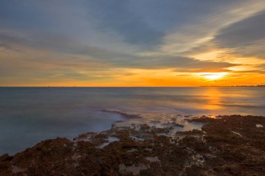 Çok Bulutlu bir gün batımı sakin denizde