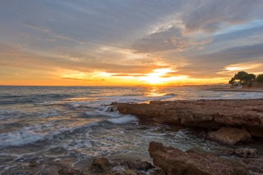 Çok Bulutlu bir gün batımı sakin denizde