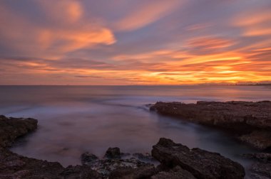 Çok Bulutlu bir gün batımı sakin denizde