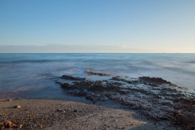 Çok Bulutlu bir gün batımı sakin denizde