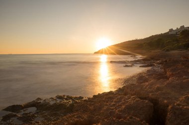 Çok Bulutlu bir gün batımı sakin denizde