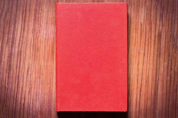 Um livro vermelho em uma mesa marrom — Fotografia de Stock