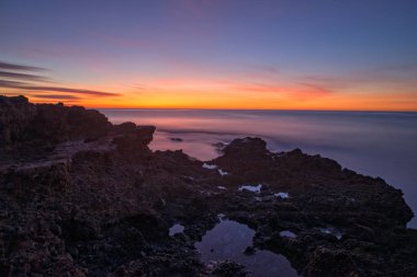 Çok Bulutlu bir gün batımı sakin denizde