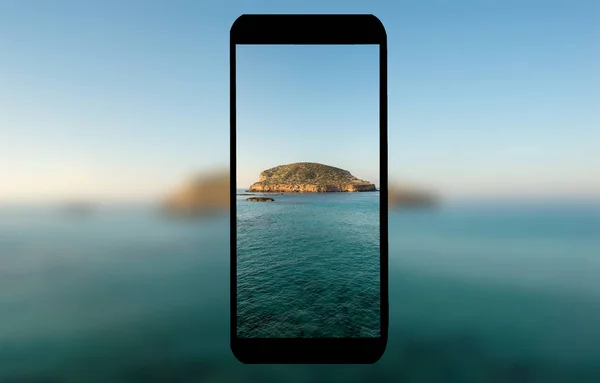 Ein Handy mit dem Meer im Hintergrund — Stockfoto