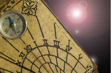 Kahverengi arka planda bir pusula ile bir güneş saati