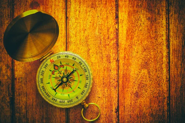 An old compass on a wooden background