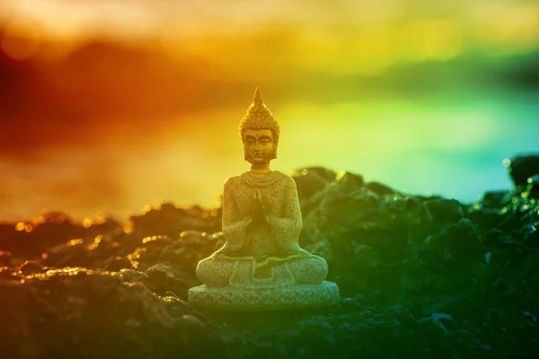 Egy napkeltekor a tenger mellett meditáló buddha alakja — Stock Fotó