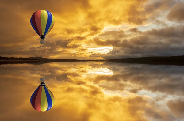 A hot air balloon over a lake at sunrise — 스톡 사진