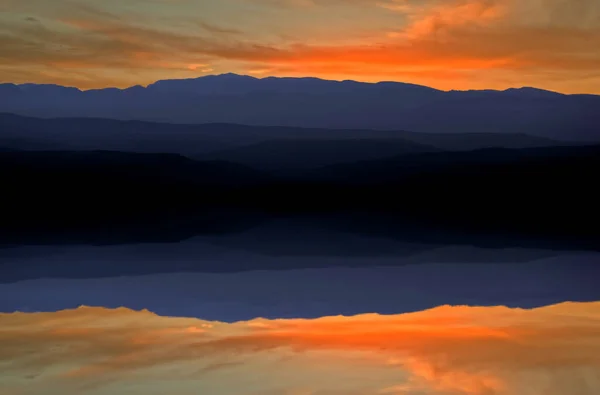 Zachód słońca nad jeziorem pod czerwonym i niebieskim niebem — Zdjęcie stockowe